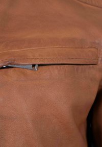 Braune Lederjacke mit einem Reißverschlussfach, glatter Textur und enganliegendem Design mit detaillierter Nahtführung entlang der Nähte.