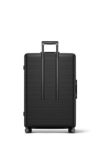 Black hard-shell suitcase with vertical stripes, extendable handle, and spinner wheels. Features a side handle for easy lifting.
