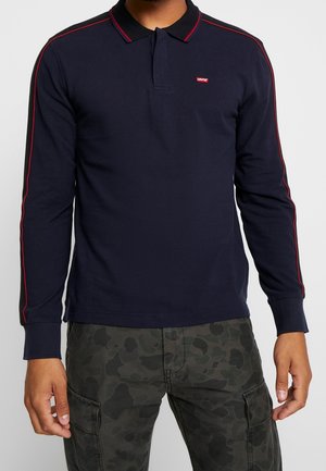 Marineblaues Polohemd mit langen Ärmeln und roten Akzentstreifen, mit schwarzem Kragen und kleinem Levi's-Logo auf der Brust. Strukturierter Stoff.