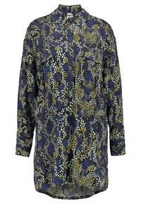 Camicia a maniche lunghe con bottoni di colore blu navy, decorata con un motivo astratto di forme gialle e verde chiaro. Presenta un colletto e due tasche frontali.