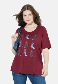 Camiseta burdeos de manga corta con un gráfico colorido de varias botas de vaquero. Tejido suave, escote redondeado y corte relajado.