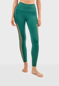 Leggings teal avec une taille haute, dotés de panneaux en maille sur les côtés pour respirabilité, fabriqués à partir d'un tissu extensible pour le confort.