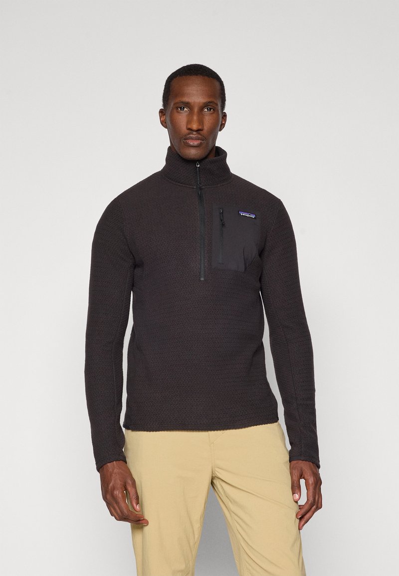 Zwarte fleece pullover met een hoge kraag, halve ritssluiting aan de voorkant en een borstzak; textuurpatroon over de hele lengte, slim fit ontwerp.