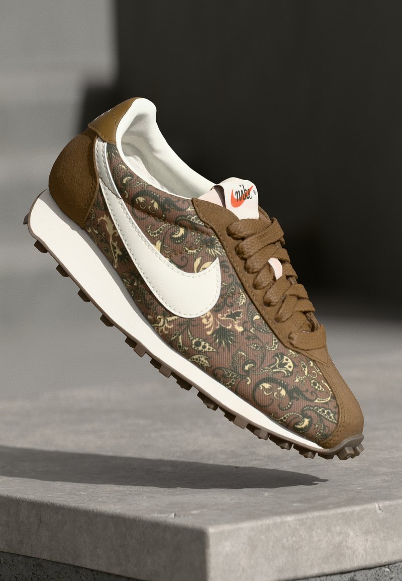 Sneaker marrone con motivo, dotato di swoosh bianco, dettagli in suede e tomaia testurizzata. Caratterizzato da un collo imbottito e suola in gomma per una migliore aderenza.