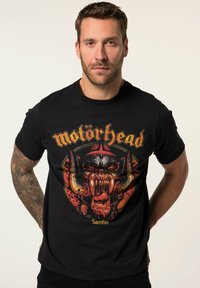 Sort bomulds T-shirt med et grafisk motiv af et vredt væsen med horn og tænder, accentueret med rød og gul tekst mærket "Motörhead."