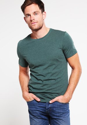 Grünes kurzärmliges T-Shirt aus weichem Stoff mit einem klassischen Rundhalsausschnitt. Kombiniert mit blauen Jeans für einen lässigen Look.