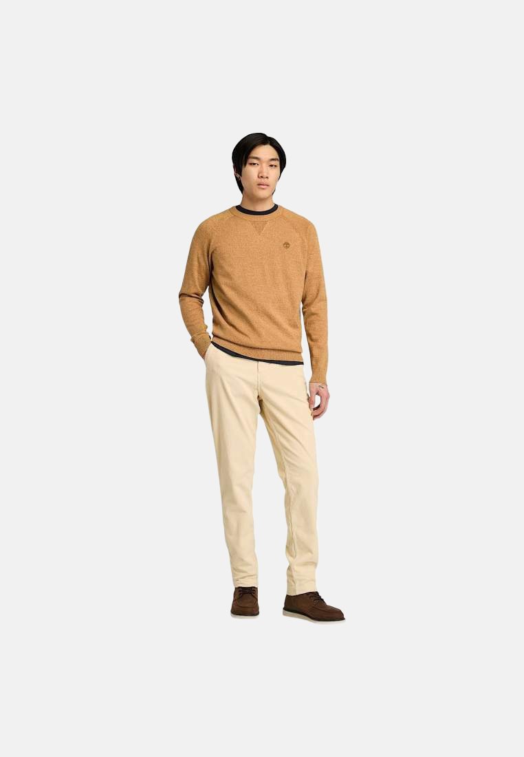 Maglione lavorato a maglia color beige con scollatura rotonda e piccolo logo, abbinato a pantaloni color crema e scarpe marroni.