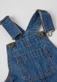 Denim tuinbroeken in een diepe blauwe tint met verstelbare bandjes, messing hardware en contrasterende oranje stiksels. Beschikt over een achterzak met label.