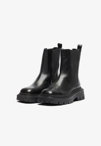 Botine negre din piele cu panouri laterale elastice, vârf rotunjit, talpă groasă din cauciuc și tab-uri pentru o purtare ușoară. Finisaj elegant și lucios.