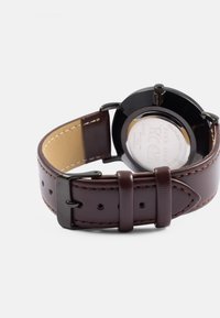 Brown leather watch strap with a black metal case and buckle, featuring a smooth, polished texture and contrasting stitching.