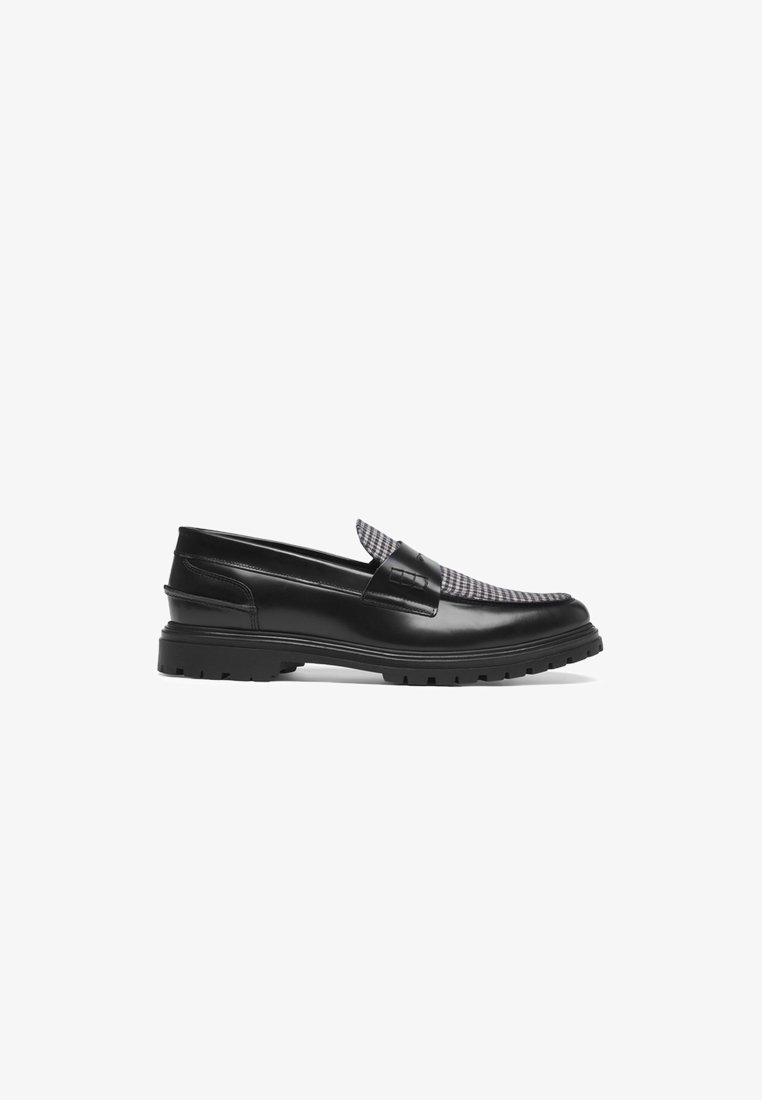 Black leather loafers with a textured grey and black checkered upper, featuring a low, chunky sole and a decorative strap detail.