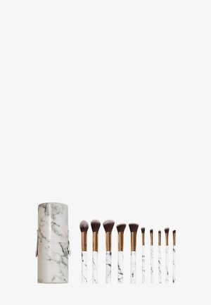 Ensemble de dix pinceaux de maquillage avec manches en marbre blanc et viroles en or rose, présenté à côté d'un étui cylindrique assorti au motif marbré.