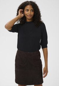 Black, fitted shirt with short, puffed sleeves paired with a brown suede skirt featuring two patch pockets. Simple, elegant design.