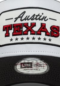 Λευκό βαμβακερό καπέλο με μαύρη ζώνη στο χείλος, με κόκκινα και μαύρα κεντημένα γράμματα που γράφουν «Austin TEXAS» και διακοσμητικά αστέρια. Ρυθμιζόμενο λουράκι στο εσωτερικό.