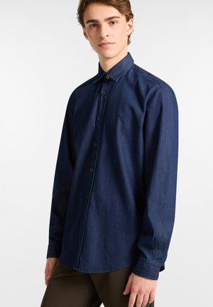 Donkerdenim overhemd met lange mouwen, een puntige kraag, een voorknopsluiting en een klein logo op de borst. Soepele textuur.
