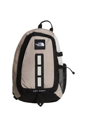 Zaino beige e nero North Face Hot Shot con striscia riflettente verticale frontale, tasca laterale in rete e maniglia superiore per il trasporto.