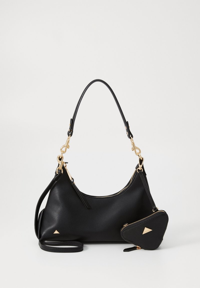 Bolso de mano de cuero negro con forma curva, herrajes dorados y un monedero triangular desmontable. Textura suave, diseño sencillo.