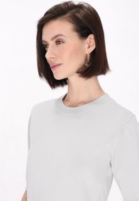 Lys grå kortærmet sweater med rund halsudskæring. Blød tekstur og minimalistisk design. Har en glat finish uden mønstre eller accenter.