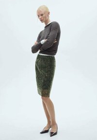 Groene slangenprint pencil skirt met een gladde textuur, gecombineerd met een strakke bruine top met lange mouwen, gedragen met spitse zwarte flats.