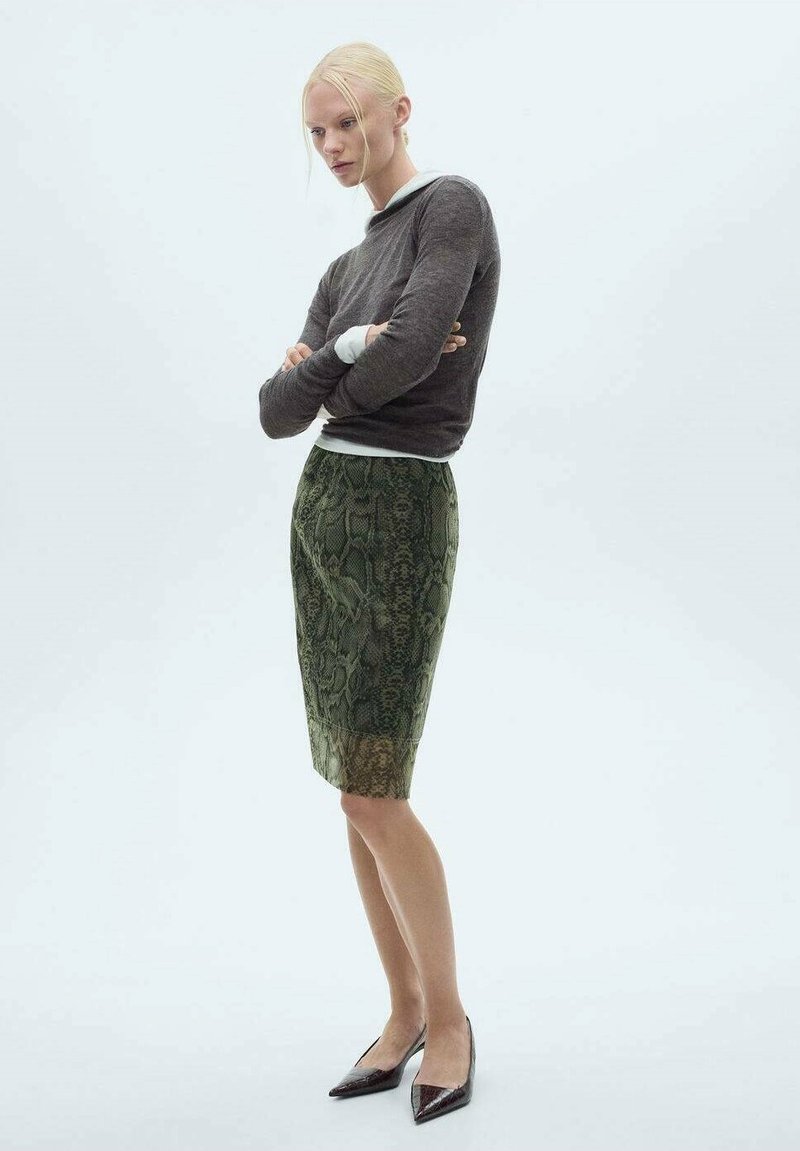 Groene slangenprint pencil skirt met een gladde textuur, gecombineerd met een strakke bruine top met lange mouwen, gedragen met spitse zwarte flats.