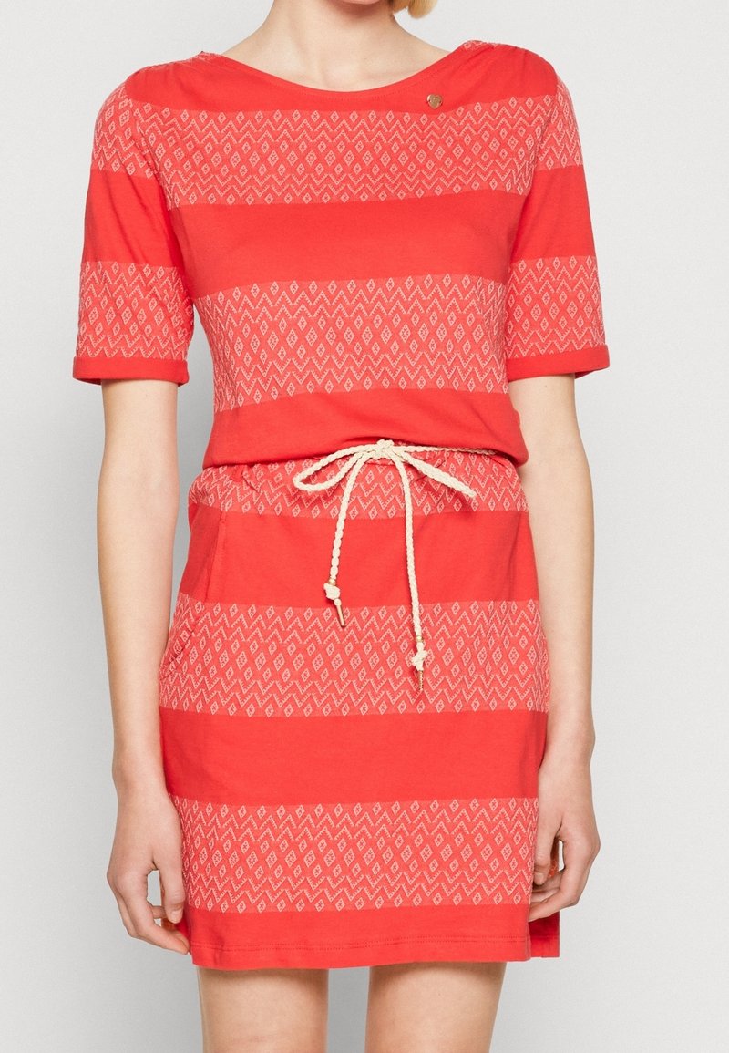 Robe rouge à manches courtes avec un motif en losange, taille cintrée et cordon de serrage. Caractérisée par un col bateau et un bouton décoratif sur l'épaule.