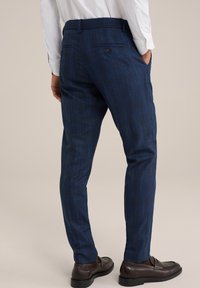 Mornarsko kariraste slim-fit hlače z teksturiranim zaključkom, žepi in enim gumbom na hrbtni strani. Kombinirane z rjavimi loaferji.