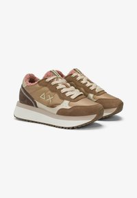 Brown suede and fabric sneakers with cream accents, plush pink lining, thick white sole, and decorative side stitching and logo details.