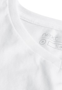 Vit kortärmad T-shirt med V-ringning, tillverkad av bomull, med en slät yta och en tvättrådsetikett inuti kragen.