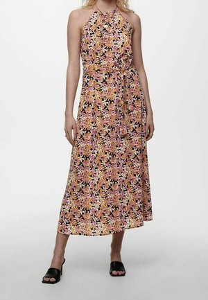 Robe longue à col halter, motif floral en rose, jaune et blanc sur fond noir, taille cintrée, tissu fluide. Sandales noires.