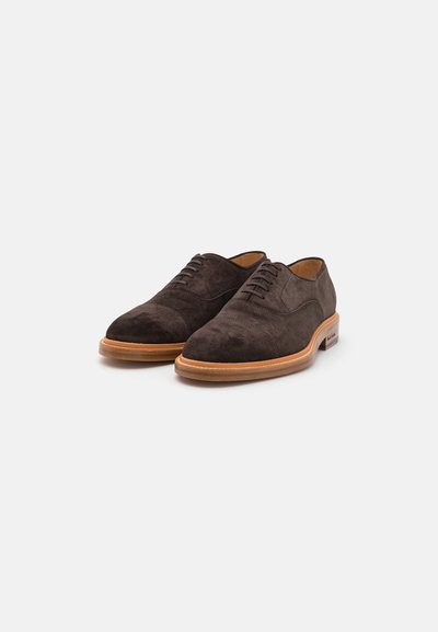 Chaussures habillées en daim marron avec des orteils arrondis, un laçage lisse et une semelle en cuir beige. Présente des coutures subtiles et une finition soignée.