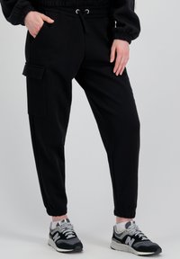 Schwarze Jogginghosen aus weichem Material, mit einem elastischen Bund und Kordelzug, Seitentaschen und einer Cargo-Tasche am Oberschenkel.