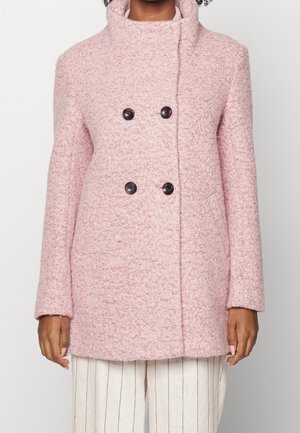 Dubbelknäppt rosa ullrock i texturerat tyg med stora svarta knappar och hög krage. Långa ärmar och rak passform.