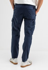 Marine cargobroek van lichtgewicht stof, met zijzakken en elastische manchetten. Draagt met witte sneakers en een plain wit top.