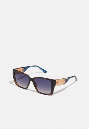 Black and brown gradient sunglasses with rectangular lenses, blue acetate arms, and a metallic GUESS logo on the temples.