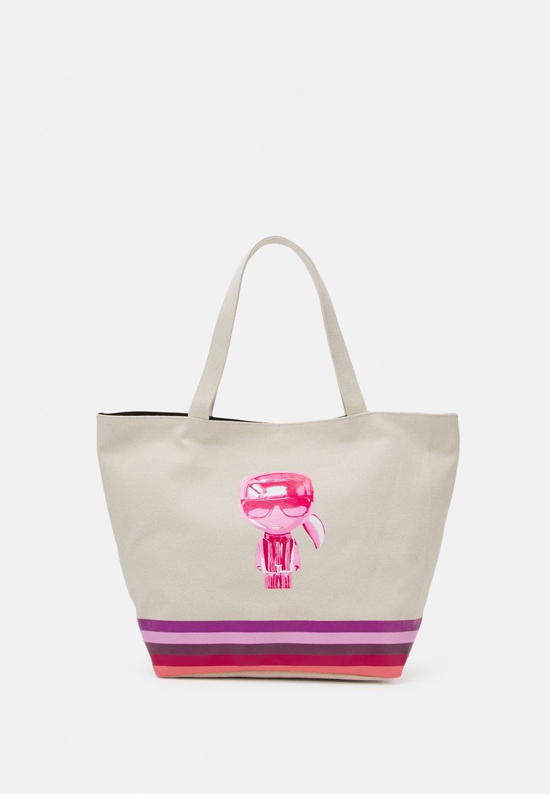 Sac fourre-tout beige avec deux poignées, représentant une figure de dessin animé rose brillante et des rayures horizontales dans des tons rouges et violets en bas.