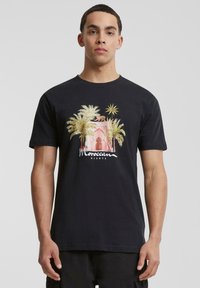 Svart bomulls T-skjorte med et fargerikt grafisk motiv av palmer og en marokkansk bygning, med teksten "Moroccan Nights" i hvitt.