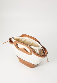 Petit sac à main blanc et beige avec intérieur en tissu doux et fermeture par cordon, doté de poignées découpées et d'un marquage en relief à la base.