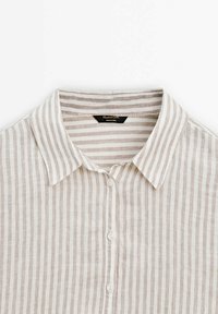 Chemise à col, boutonnée, avec des rayures verticales beige et blanches, en tissu léger en lin.