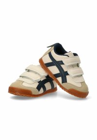 Zapatos para bebés con una parte superior de sintético blanco suave, detalles en navy, dos correas de Velcro y una suela de goma con un patrón texturizado.