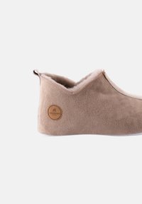 Beige Wildlederschuh mit gesticktem Design, flauschigem Innenfutter und einem runden Logo-Patch. Verfügt über eine niedrige Silhouette und eine weiche Sohle.