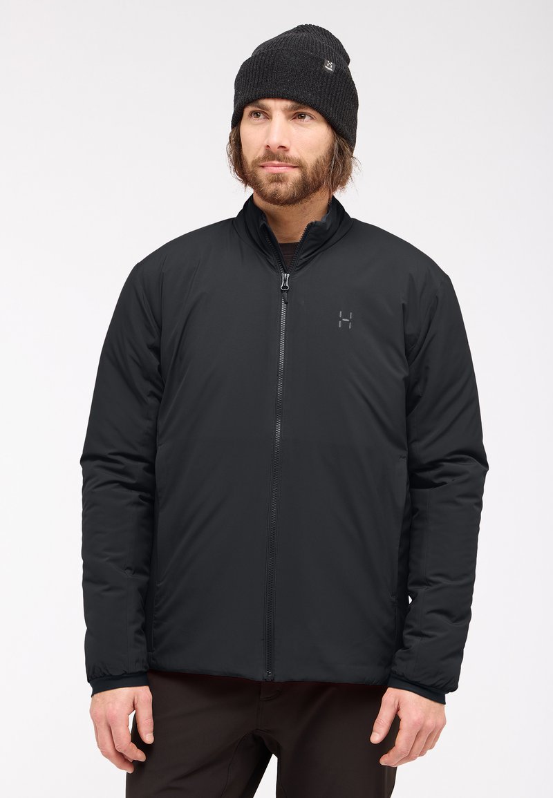 Chaqueta aislante negra con un alto cuello y cremallera frontal completa. Material suave, mangas largas y un logo sutil en el pecho.
