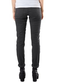 Jeans ajustados de color gris oscuro con dobladillos enrollados, que muestran un tejido suave y elástico, y bolsillos traseros con sutiles detalles de costura.