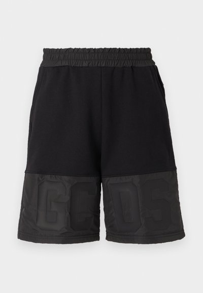 Shorts noirs avec une taille élastique, présentant un tissu supérieur lisse et une section inférieure brillante contrastante avec un grand texte "GCSD".