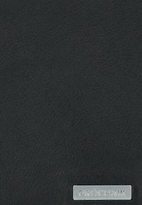 Czarna skórzana powierzchnia o teksturowanej fakturze. Na dole znajduje się srebrna, metaliczna metka marki "PRÓCHNIK". Prostokątny kształt.