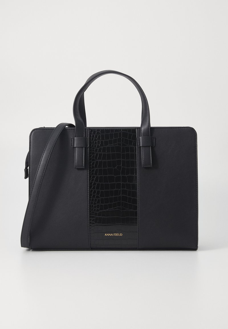 Sac à main noir avec une finition lisse et un panneau en texture crocodile au centre. Équipé de doubles poignées et d'une bandoulière réglable.