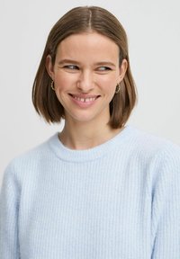 Helles blaues geripptes Sweatshirt mit rundem Ausschnitt, aus weichem Material gefertigt, mit einer lockeren Passform. Dezentes Texturmuster über das gesamte Teil.