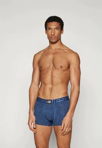 Boxeri scurți cu model albastru, cu o textură netedă și talie elastică. Prezintă un design geometric și un logo pe talie.