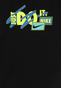 Tela negra que presenta gráficos audaces y multicolores que incluyen "JUST DO IT" en amarillo neón, superpuestos con un acento azul y logos de Nike.