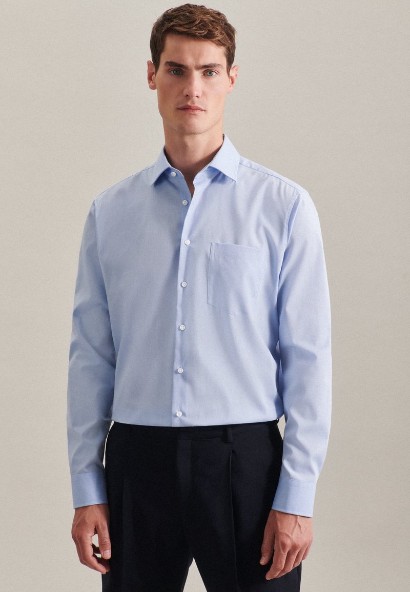Light blue long-sleeve shirt made of cotton, featuring a button-down collar, front pocket, and white buttons against a plain background.