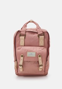 Pink fabric backpack with beige leather accents, dual side pockets, top handle, adjustable straps, and a front flap with a logo patch.
